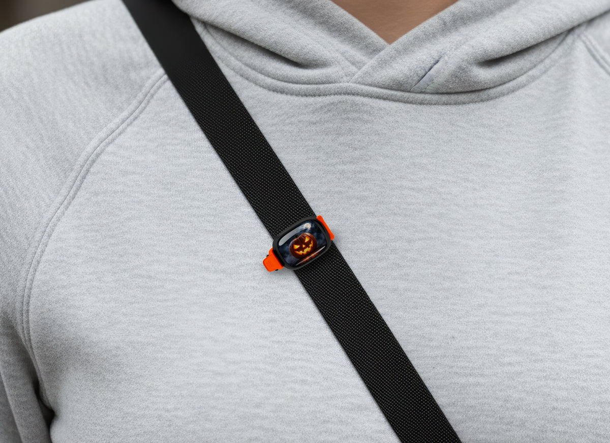 Glowing Jack O Lantern Stwrap bag tag on a diagonal black strap over a gray sweatshirt