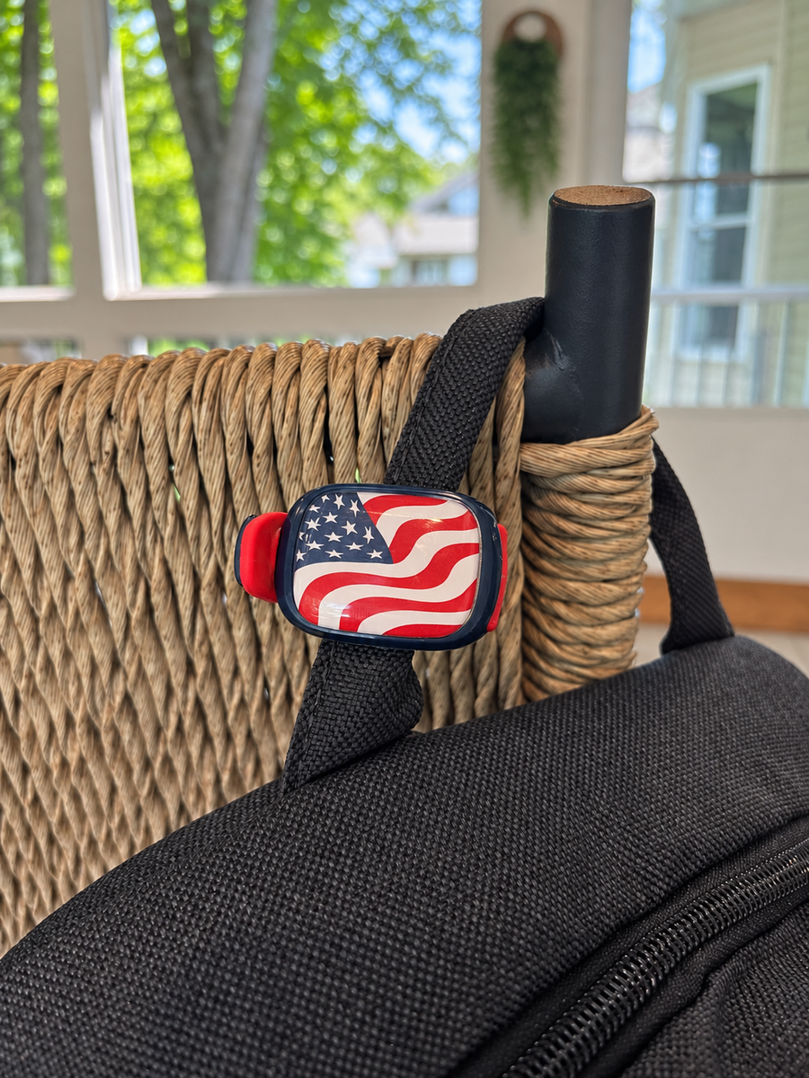 Flag Stwrap attached flat to a black bag strap beside a wicker chair