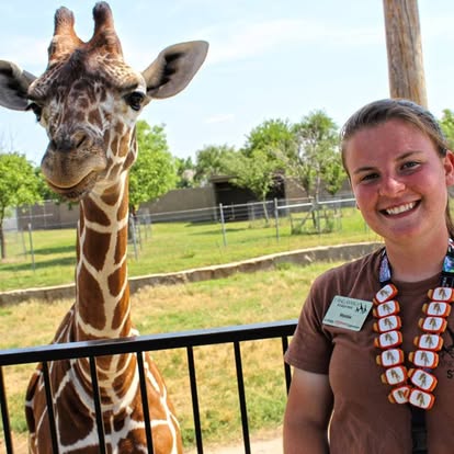 Tanganyika Wildlife Park team member beside a giraffe wearing collectible animal Stwraps on a lanyard